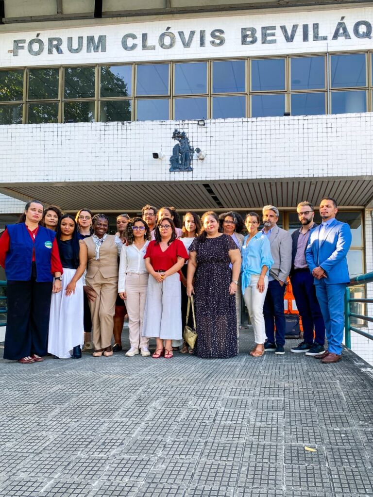Foto colorida dos defensores de direitos humanos perfilados em frente ao fórum de Fortaleza
