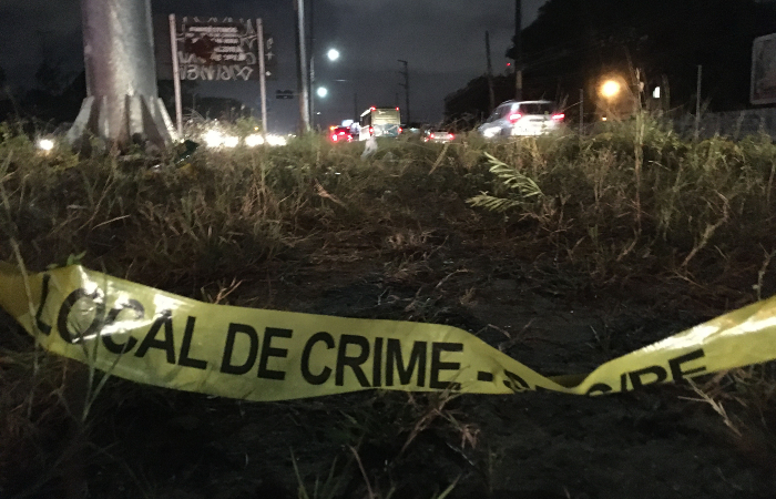 Foto colorida, à noite, em ambiente escuro, de uma cena de crime mal isolada